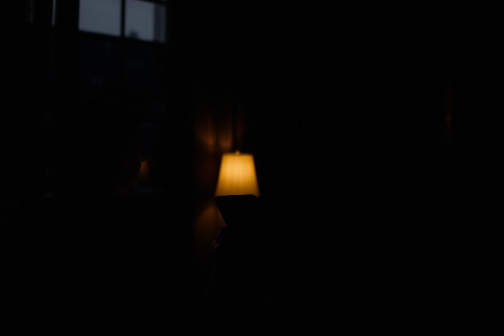 Persona reflexionando en la noche con su teléfono en la mano